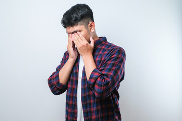 Asian young man wearing casual shirt with sad expression covering face with hands while crying. depression concept
