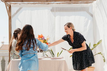 Mother and daughters setting table outdoors in spring