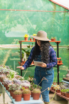 Woman wearing a hat using a tablet in her plant store