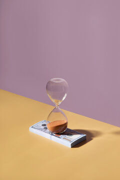 Sand clock on a pile of dollars