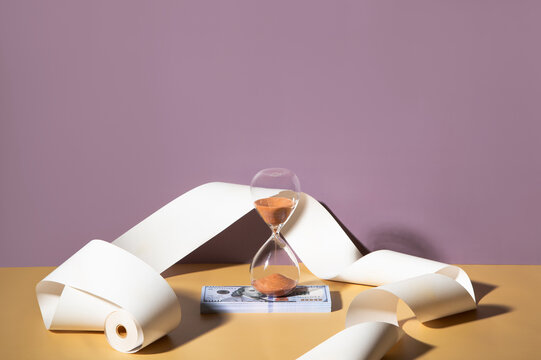 Sand clock on a pile of dollars