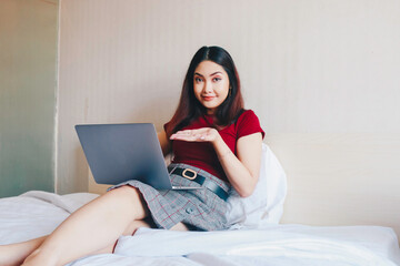 Young Asian businesswoman smiling while working on laptop computer at home. Portrait of positive business woman looking at laptop screen indoors