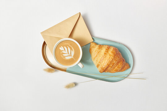Tray with cappuccino, croissant, envelope and wheat ears