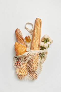 String shopping bag with bread, flowers and jar of honey