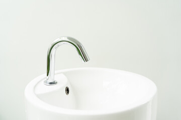 Hygienic wash basin with chrome faucet on bathroom window background. White hand washing sink