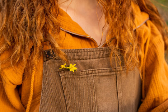 Crop image of overal pocket with flowers and ginger long hair