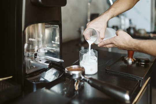 Hands pouring milk for iced latte - Powered by Adobe