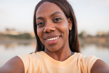 UGC of a 30 year old black woman taking a selfie by a river