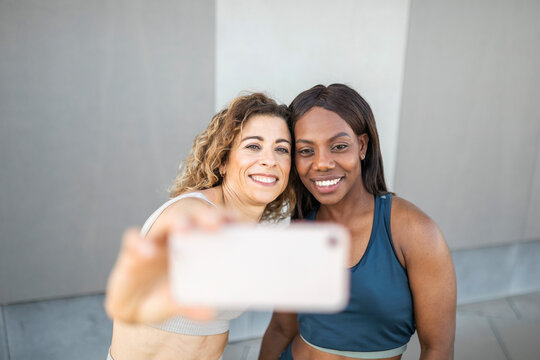 Caucasian woman and black woman with their faces together taking a sel