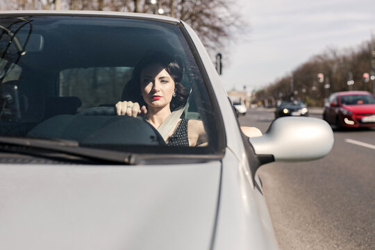 Confident beautiful woman at camera from her car