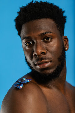 Man shirtless with blue butterfly perched on shoulder