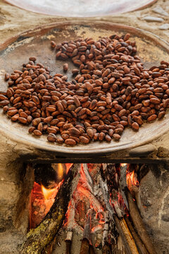 Cacao beans roasting on a comal with the intense fire below