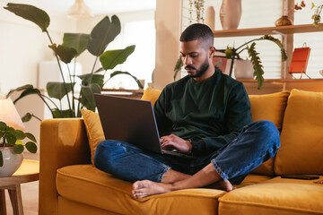 Barefoot black freelancer working on sofa