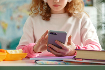 Crop schoolgirl browsing social media on cellphone