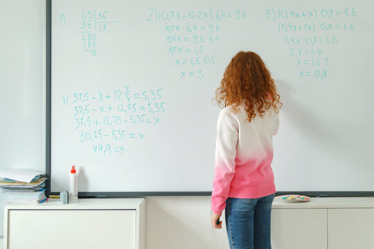 Girl solving equations on whiteboard