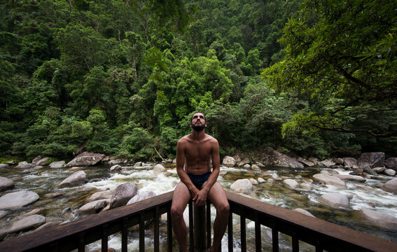 Sitting man looking up on a balcony near tropical river
