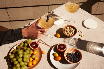 Person holding a cocktail glass among different foods