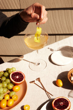 Fototapeta Person holding a cocktail glass among different foods