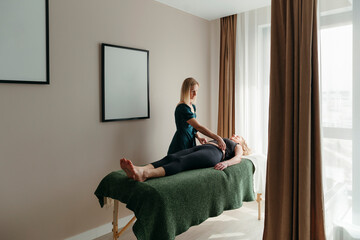Woman osteopath works with senior female client.