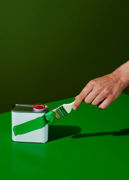 man painting green a white motor oil can