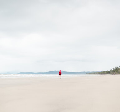 Minimal portrait of distant woman walking on solitary beach