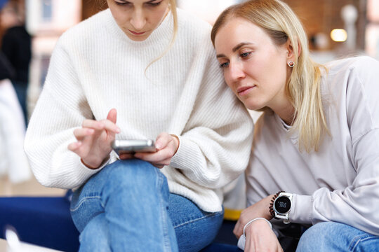 Girls browsing information in mobile phone 