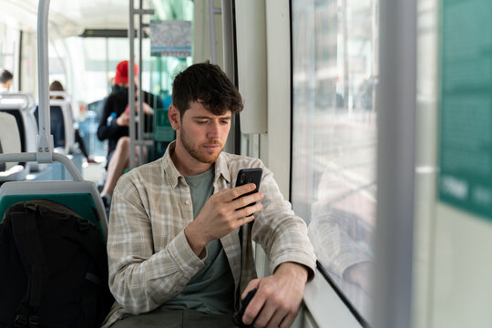 Man using smartphone traveling by tram