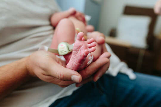 Dad holds tiny foot of newborn baby