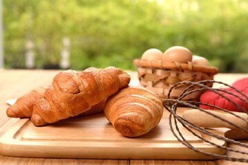 croissant on wooden board with egg blasket with blur green background