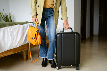 Cropped female with travel suitcase at home