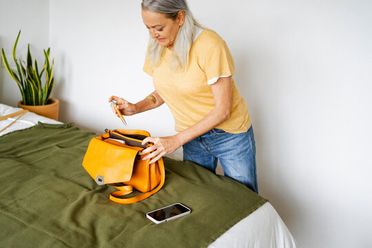 Senior woman preparing bag in bedroom
