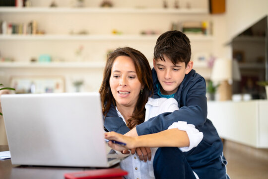 Teenager watching mother using laptop