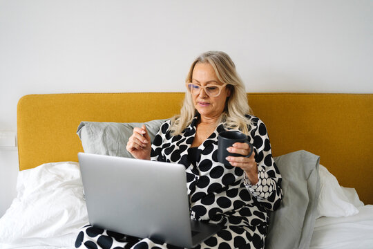 Senior woman with laptop bedridden