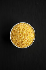 Raw Organic Risoni Pasta in a Bowl on a black background, top view. Flat lay, overhead, from above.