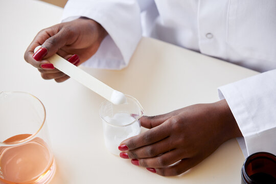 Anonymous black pharmacist making skincare product
