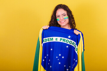 Woman soccer fan, fan of brazil, world cup, holding flag and displaying order and progress.