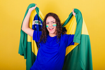 Woman soccer fan, fan of Brazil, world cup, dancing with flag on her back, celebrating victory.