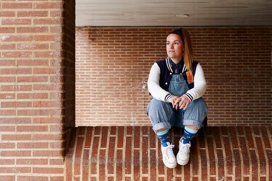 Young woman sitting outside on a brick wall 