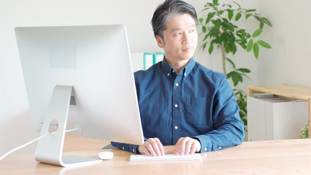 デスクトップパソコンで作業をするダンディな日本人男性