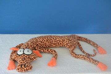 Leopardo acostado , juguete , animal , de tela , suave , blando, marrón , naranja , negro , azul , blanco , regalo , divertido, jugar , niños , abrazo , regalar   
