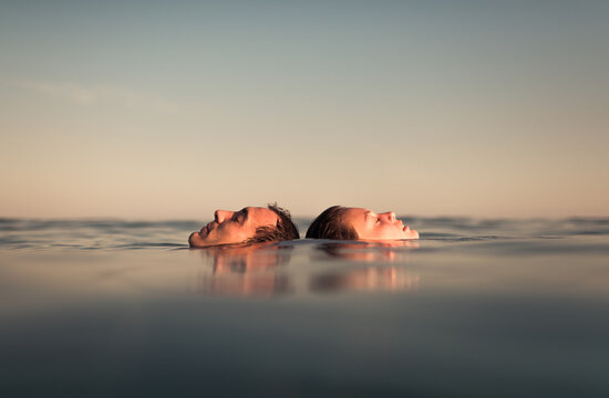 Relaxed couple floating together on the sea enjoying the calm - Powered by Adobe