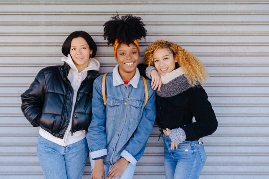 Cheerful multiethnic friends over metallic background