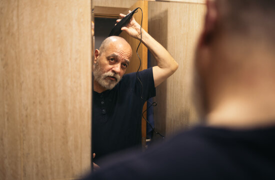 Mature man shaving his hair with a clipper
