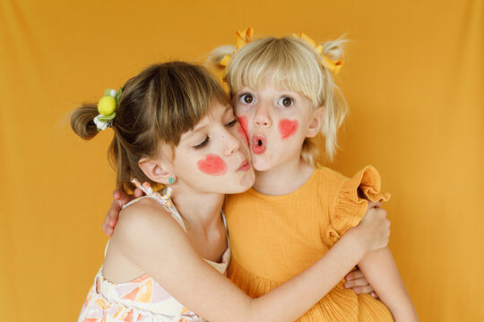 Portrait of two little girls over yellow backdrop