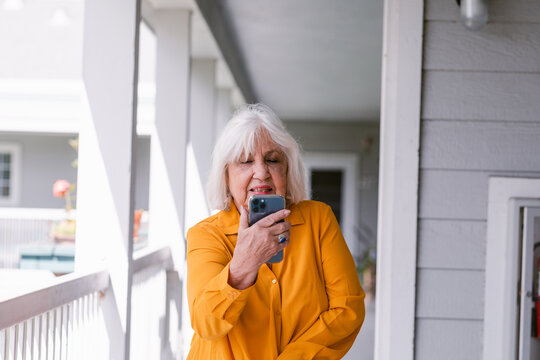 Modern senior woman using mobile phone outside residence
