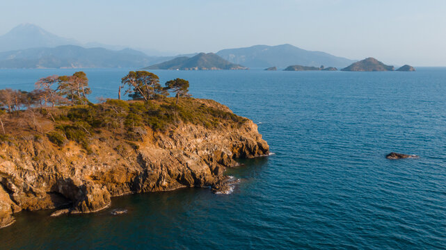 scenic landscape with rock cliffs and pines surrounded by blue sea