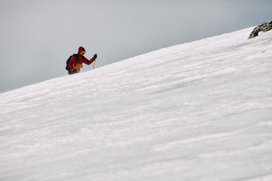 Male Solo Adventurer Ascending Windy Mountain on Skis