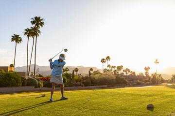 Beautiful swing on Senior Citizen Woman Playing Golf in morning 