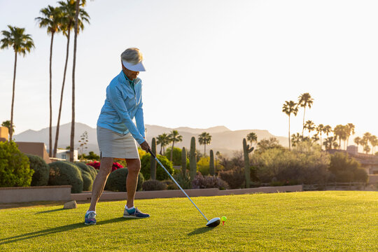 Backlit Senior Citizen Woman Playing Golf in morning hours 