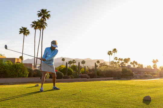Backlit Senior Citizen Woman Playing Golf with driver club 